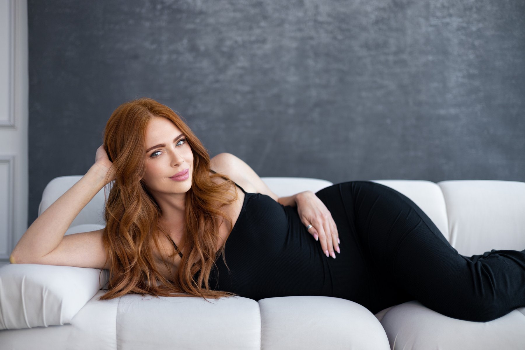 Rachel London reclining on a cream sofa.